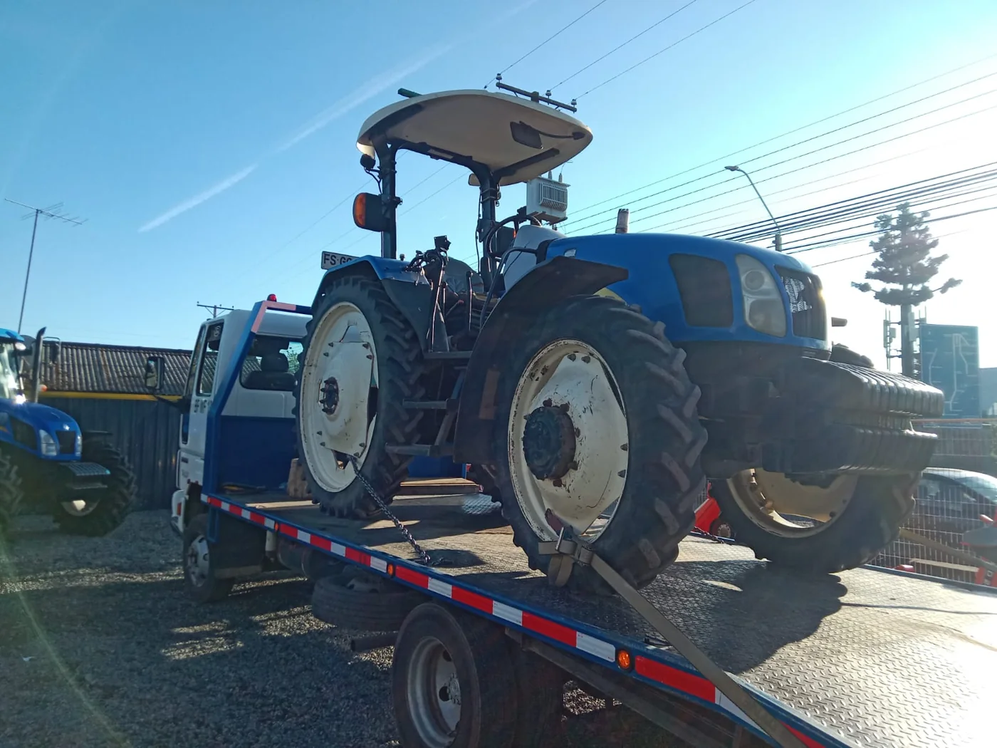 Grúa trasladando tractor azul